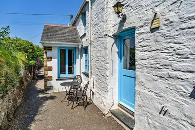 a small house with a blue door and a table at Finest Retreats - Forge Cottage, Padstow in Padstow
