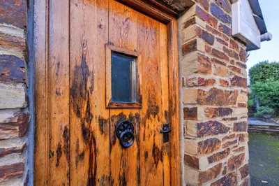 a wooden door with a mask on a brick building at Finest Retreats - Forge Cottage, Padstow in Padstow