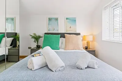 a bedroom with a bed with white and green pillows at Kimberley Cottage - Stylish cottage & parking in Falmouth