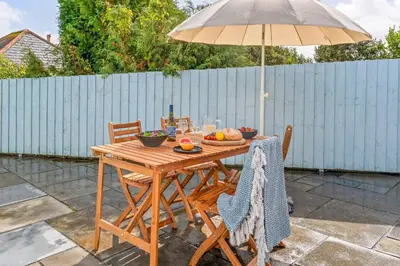 a wooden table with an umbrella on a patio at Kimberley Cottage - Stylish cottage & parking in Falmouth
