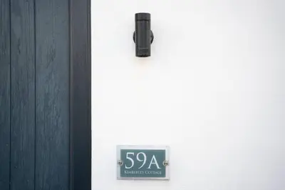 a sign on the side of a door with a sign on it at Kimberley Cottage - Stylish cottage & parking in Falmouth