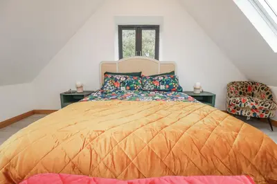 a bedroom with a large bed and a chair at Barn 2 in St Austell