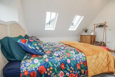 a bedroom with a bed with a floral comforter at Barn 2 in St Austell