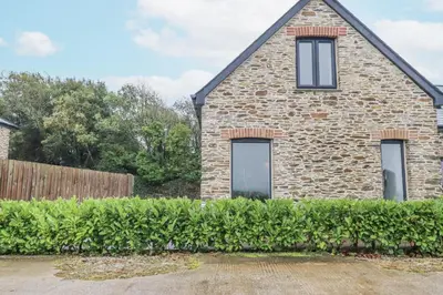 a brick house with two windows and a hedge at Barn 2 in St Austell
