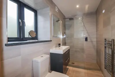 a bathroom with a toilet and a sink and a window at Barn 2 in St Austell