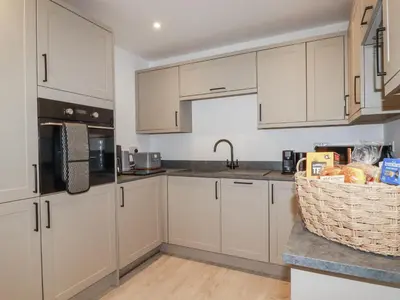 a kitchen with white cabinets and a basket of food at Barn 2 in St Austell
