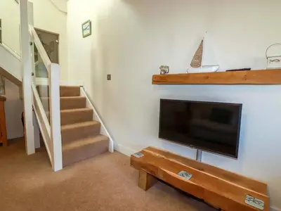 a living room with a flat screen tv and stairs at 3 The Old Cornstore in St. Agnes