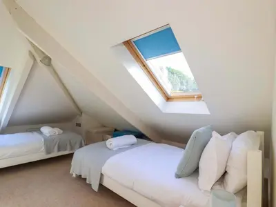 a attic bedroom with two beds and a window at 3 The Old Cornstore in St. Agnes
