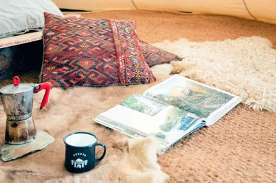 a pile of items on the floor with a coffee mug and a book at Shanti Tipi 2 in Tintagel