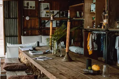 a living room with a wooden table and clothes racks at Shanti Tipi 2 in Tintagel