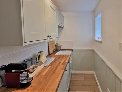 a kitchen with white cabinets and a wooden counter top at The Bolthole in Fowey