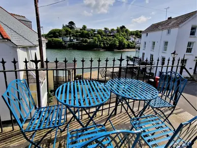 a table and chairs with a fence and water at The Bolthole in Fowey