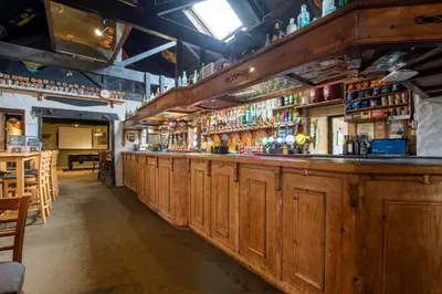 a bar with wooden cabinets in a restaurant at Tricky's at The Tolgus Inn, Redruth - Free WiFi - Free Parking in Redruth