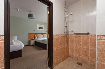 a bathroom with a shower and a bedroom with a bed at Tricky's at The Tolgus Inn, Redruth - Free WiFi - Free Parking in Redruth