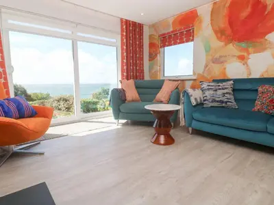 a living room with two blue couches and a table at Shearwater in Penzance