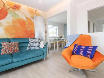 a living room with a blue couch and an orange chair at Shearwater in Penzance
