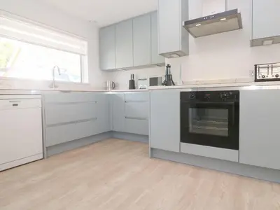 a white kitchen with white cabinets and an oven at Shearwater in Penzance