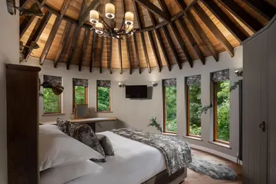 a bedroom with a large bed and windows at Landal Clowance in Crowan