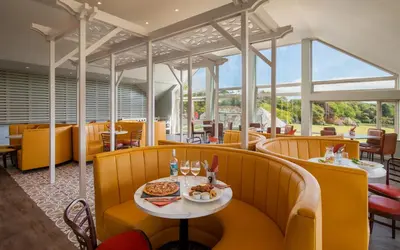 a restaurant with yellow chairs and a table with food at Landal Clowance in Crowan