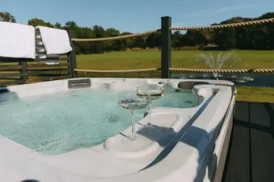 a hot tub with two wine glasses in it at Landal Clowance in Crowan