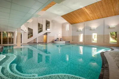 a large swimming pool with blue water in a building at Landal Clowance in Crowan