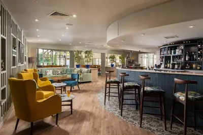 a bar in a restaurant with yellow chairs and tables at Landal Clowance in Crowan