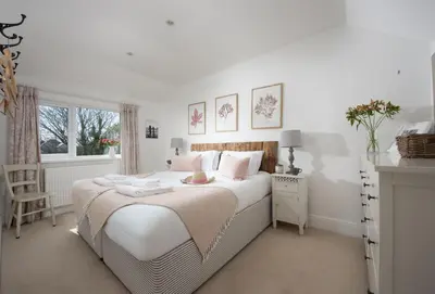 a bedroom with a large white bed with pink pillows at Little Tresevens in Polzeath