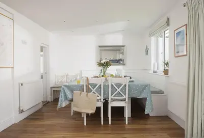 a white dining room with a blue table and chairs at Little Tresevens in Polzeath