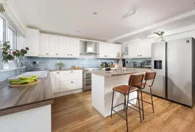 a kitchen with white cabinets and a stainless steel refrigerator at Little Tresevens in Polzeath