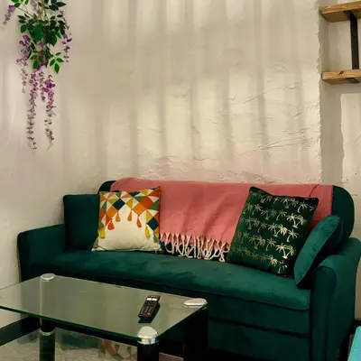 a green couch with pillows and a glass table at Turtle retreat in Falmouth