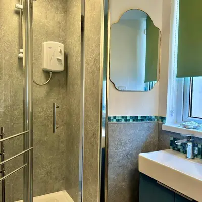 a shower with a glass door next to a sink at Turtle retreat in Falmouth
