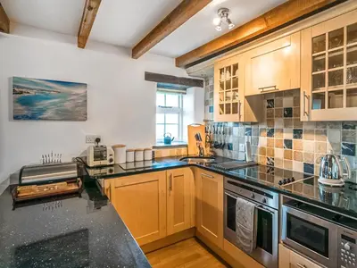 a kitchen with wooden cabinets and a black counter top at Wharrastone - Uk50661 in Bude
