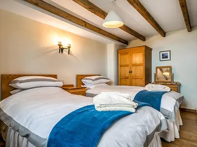 two twin beds in a room with wooden ceilings at Wharrastone - Uk50661 in Bude