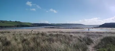 a beach with people walking in the water at Peace Haven in Par