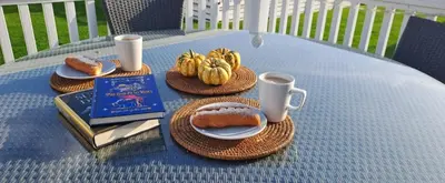 a table with plates of food and cups and a book at Blue Lagoon Holiday ,Bude 79 in Cubert