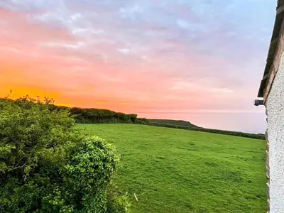 a field of green grass with a sunset in the background at Raddons - Uk50657 in Bude