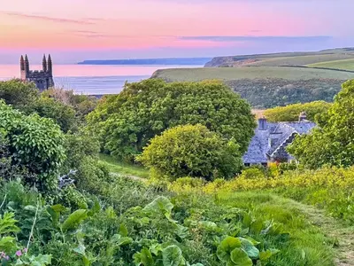 a house in a field with the ocean in the background at Raddons - Uk50657 in Bude