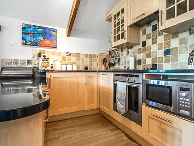 a kitchen with wooden cabinets and stainless steel appliances at Raddons - Uk50657 in Bude