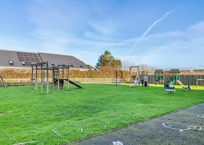 a playground with two swings and a slide at Bay Retreat Villas in St Merryn
