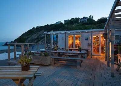 a deck with picnic tables and a house on the beach at Millendreath Beach Resort in Saint Martin