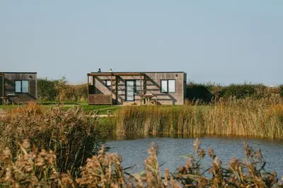 a house in a field next to a body of water at Landal Gwel an Mor in Portreath