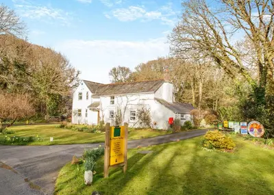 a white house with a yellow sign in the yard at Ruthern Valley Holidays in Withiel