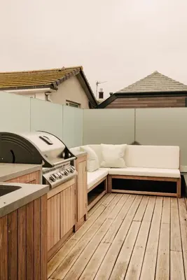 a patio with a white couch and a grill at Seaside Cottage in St Ives in St Ives