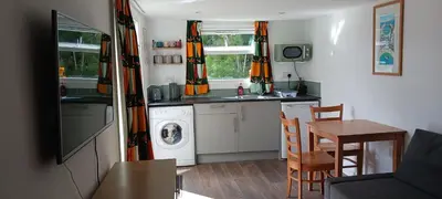 a small kitchen with a washing machine and a table at Chy An Geddon in Penryn