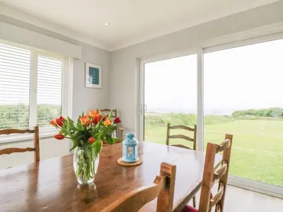 a dining room with a table with a vase of flowers at Chynoweth in Crantock