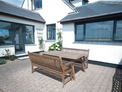a wooden bench sitting in front of a house at Chynoweth in Crantock