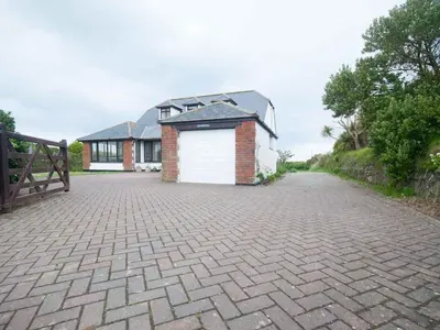 a brick house with a garage on a driveway at Chynoweth in Crantock