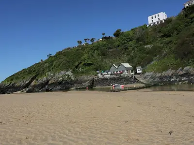a beach with a house on top of a hill at Chynoweth in Crantock