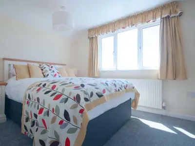 a bedroom with a bed and a large window at Chynoweth in Crantock