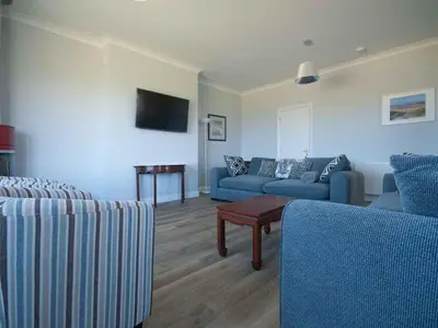 a living room with two blue couches and a table at Chynoweth in Crantock